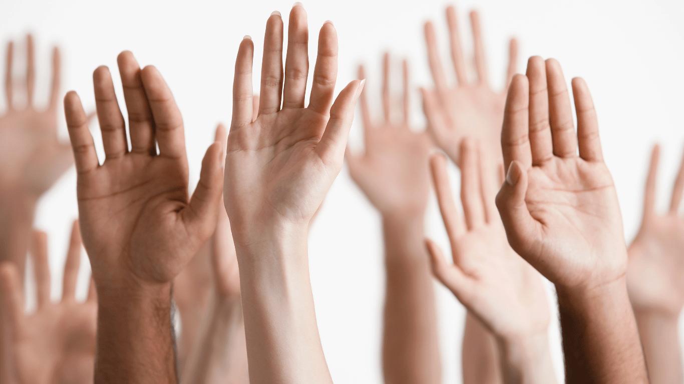 A group of people raising their hands in the air.